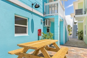 A narrow outdoor corridor with a wooden picnic table and a red mailbox. - Poolside Fun, Pickleball & Coastal Adventures Await in Fort Myers - Jefferson Palms 125-3  - Roelens (Fort Myers Beach)