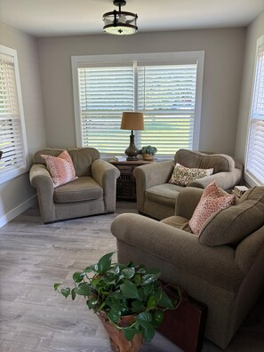 A room with two armchairs, a side table with a lamp, and a potted plant. - Lake Norman 3 bed/bath cottage with private parking for cars with boat trailers (Lake Norman of Catawba)