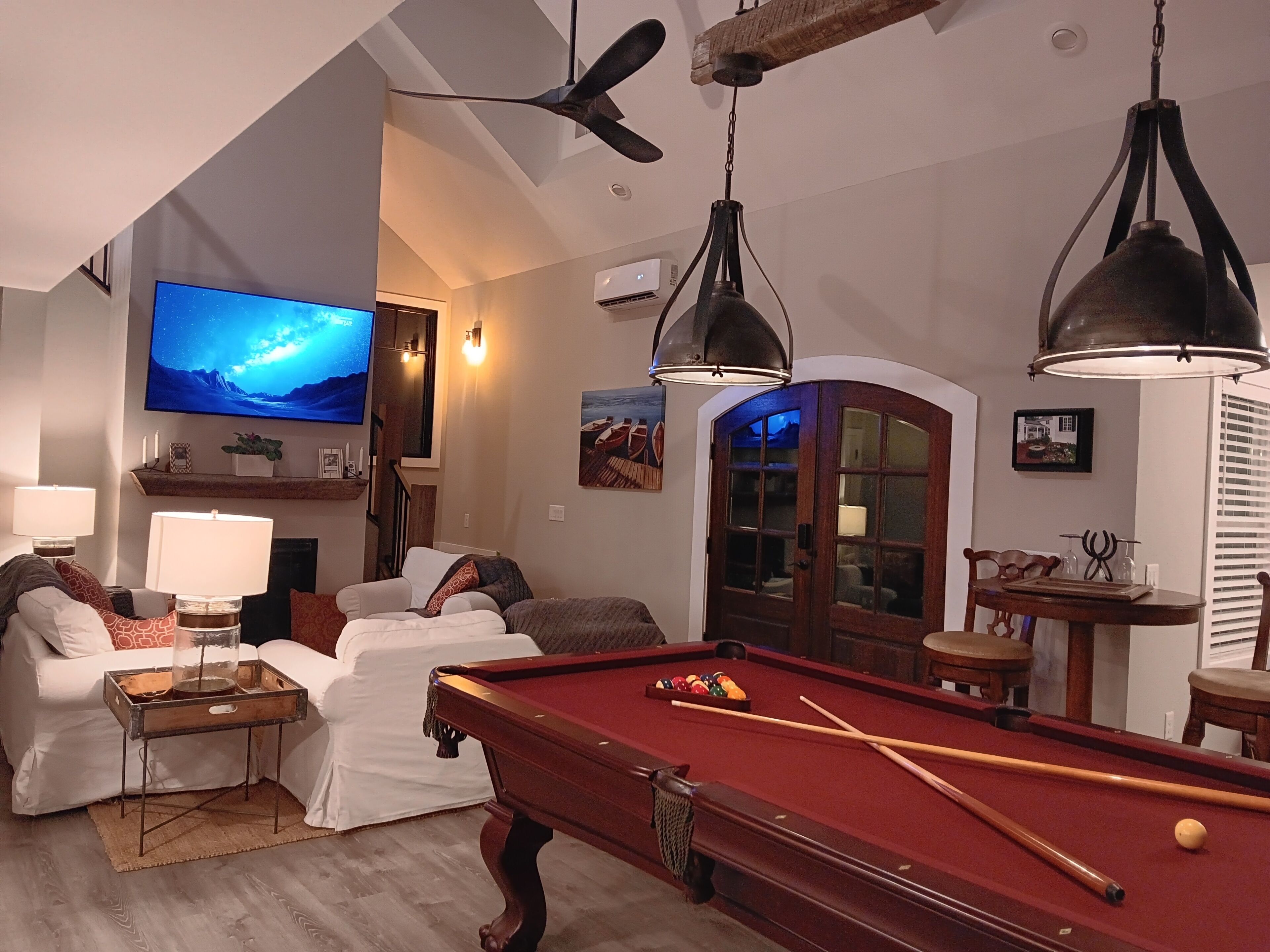 A living room with a pool table, a television, and a fireplace.