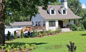 A two-story house with a front porch, a covered porch area, and a small front yard with a lawn and some shrubs. - Lake Norman 3 bed/bath cottage with private parking for cars with boat trailers (Lake Norman of Catawba)