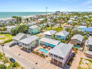 A residential area with houses, a swimming pool, and a beach in the background. - Poolside Fun, Pickleball & Coastal Adventures Await in Fort Myers - Jefferson Palms 127 - Roelens (Fort Myers Beach)