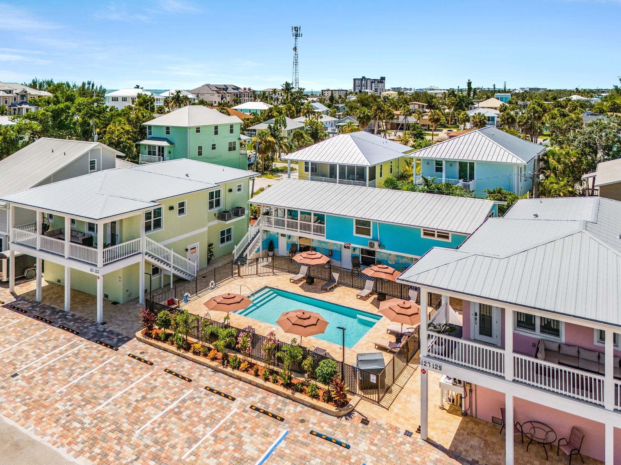 A resort with a swimming pool, multiple buildings, and a clear view of the surrounding area.