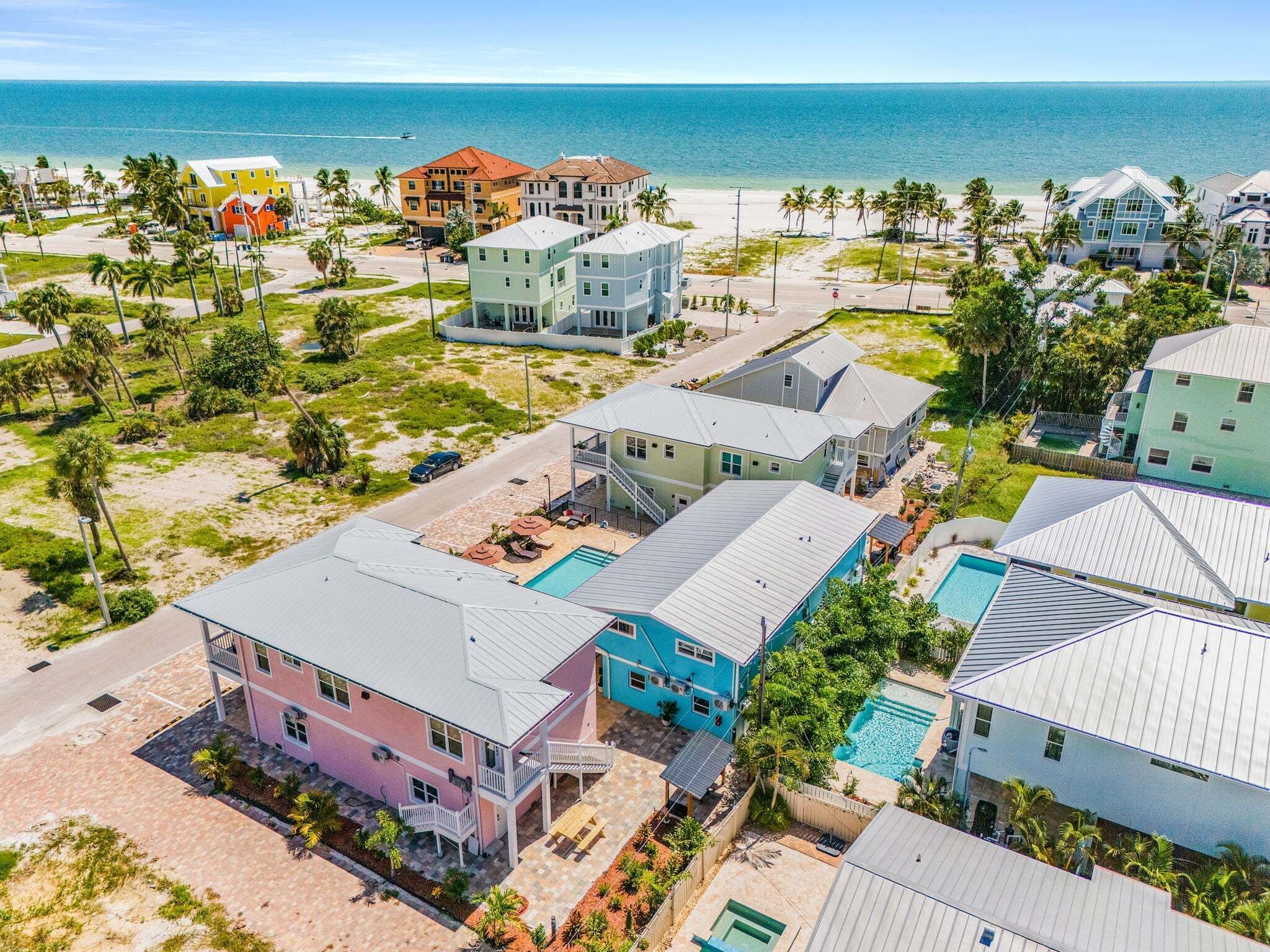 Zona residencial costera con casas, una piscina y una playa al fondo.