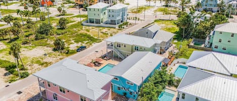 A coastal residential area with houses, a swimming pool, and a beach in the background.