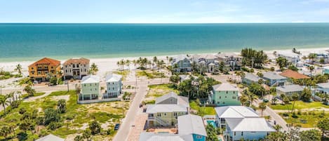 A coastal residential area with multiple houses, a beach, and a clear view of the ocean.