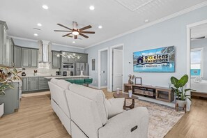 Une cuisine moderne avec des meubles gris, un îlot central et un ventilateur de plafond.