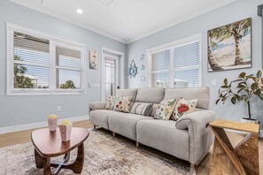A living room with a sofa, a coffee table, and a painting on the wall. - Poolside Fun, Pickleball & Coastal Adventures Await in Fort Myers - Jefferson Palms 129 - Roelens (Fort Myers Beach)