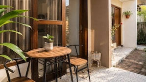 A small outdoor seating area with a table and chairs, a potted plant, and a wicker basket.