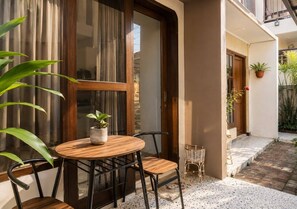 A small outdoor seating area with a table and chairs, a potted plant, and a wicker basket.