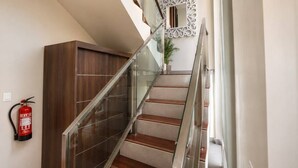 A modern staircase with glass railings, wooden steps, and a decorative mirror.