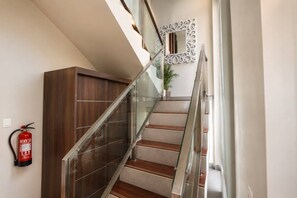 A modern staircase with glass railings, wooden steps, and a decorative mirror.