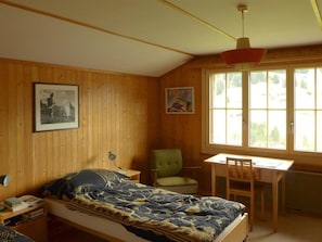 A room with a bed, a desk, a chair, and two windows. - Lucie 4-Zimmerwohnung by Interhome (Adelboden)