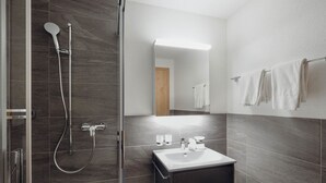 A modern bathroom with a glass shower enclosure, a sink with a mirror, and a towel rack. - Chalet Bärgfride Appartement/Fewo, Dusche, WC, 1 Schlafraum 3-Zimmerwohnung by Interhome (Kandersteg)