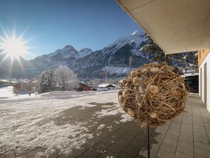 A snowy landscape with a mountain in the background, a clear sky, and a decorative spherical structure on a tiled floor. - Chalet Bärgfride Appartement/Fewo, Dusche, WC, 1 Schlafraum 3-Zimmerwohnung by Interhome (Kandersteg)