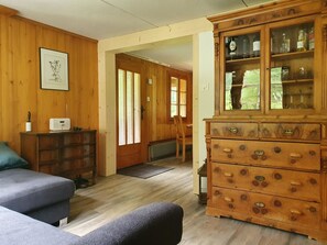 A wooden-paneled room with a sofa, a cabinet with glass doors, and a framed picture on the wall. - Schwendli Appartement/Fewo, Dusche, WC 3-Zimmerwohnung by Interhome (Kandersteg)