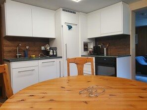 Eine moderne Küche mit weißen Schränken, einem Holzespeisetisch und einem schwarzen Backofen.