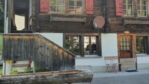 A wooden building with a sloped roof, multiple windows with shutters, and a satellite dish. - Schwendli Appartement/Fewo, Dusche, WC 3-Zimmerwohnung by Interhome (Kandersteg)