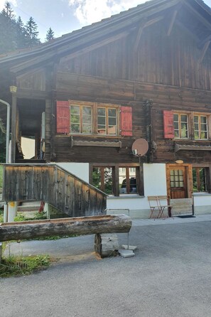 A wooden building with a sloped roof, multiple windows with shutters, and a satellite dish. - Schwendli Appartement/Fewo, Dusche, WC 3-Zimmerwohnung by Interhome (Kandersteg)