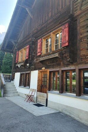 A wooden building with multiple windows and a staircase leading to the entrance. - Schwendli Appartement/Fewo, Dusche, WC 3-Zimmerwohnung by Interhome (Kandersteg)