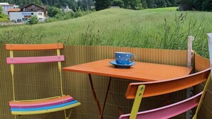 A colorful outdoor seating area with a table and chairs, overlooking a mountainous landscape. - Schwendli Appartement/Fewo, Dusche, WC 3-Zimmerwohnung by Interhome (Kandersteg)