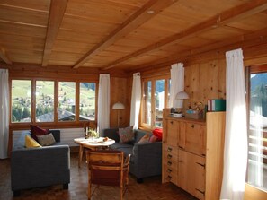 A wooden interior with a dining area, sofas, and a view of the outdoors. - Hubelhüsi Appartement/Fewo, Dusche oder Bad, WC, 4 oder mehr Schlafräume by Interhome (Adelboden)