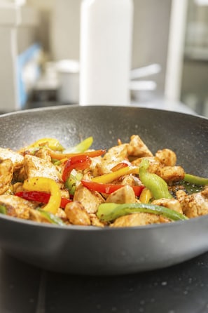 A stir-fry dish with chicken and bell peppers in a pan. - Schermtanne Appartement/Fewo, Bad, WC, 1 Schlafraum Wohnung Nr 4 by Interhome (Adelboden)
