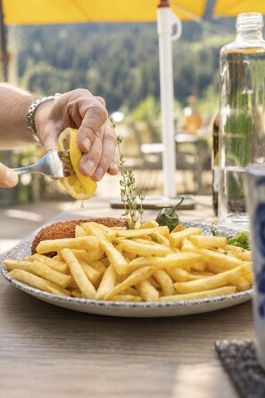 A person squeezing lemon over a plate of fries and bread. - Schermtanne Appartement/Fewo, Bad, WC, 1 Schlafraum Wohnung Nr 4 by Interhome (Adelboden)