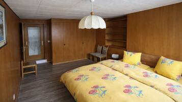 Une chambre à coucher comprenant un lit, une chaise, une armoire et un luminaire fixé au plafond.