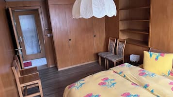 Une chambre à coucher comprenant un lit, une chaise, une armoire et un luminaire suspendu.