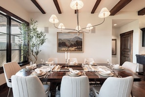 A dining room with a wooden table set for six, surrounded by six chairs, a chandelier, and a painting on the wall. - Ski-in/ski-out 3BR condo in Park City's Silver Star. (Park City)