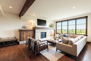 A spacious living room with a stone fireplace, a large window offering a view, and a cozy seating area. - Ski-in/ski-out 3BR condo in Park City's Silver Star. (Park City)