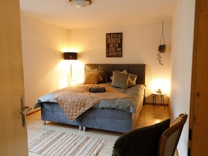 A bedroom with a bed, bedside lamps, a wall sign, and a hanging plant. - Mountain View Appartement/Fewo, Dusche, WC, 3 Schlafräume 4.5 Zimmer-Wohnung by Interhome (Frutigen)