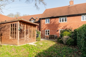 A brick house with a wooden conservatory and a garden.