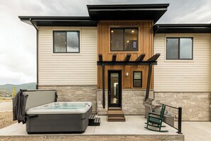 A modern house with a hot tub, a wooden porch, and a stone wall. - Deer Valley townhome with 4 bedrooms, hot tub, ski views. (Heber City)