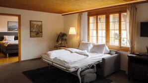 Een slaapkamer met een bed, nachtkastje, lamp, raam en een schilderij aan de muur.