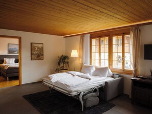 Ein Schlafzimmer mit Bett, Nachttisch, Lampe, Fenster und einem Bild an der Wand.