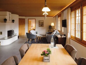 A modern living room with a wooden dining table, sofas, and a fireplace. - Alba Appartement/Fewo, Dusche und Bad, WC, 1 Schlafraum 2.5-Zimmerwohnung by Interhome (Frutigen)
