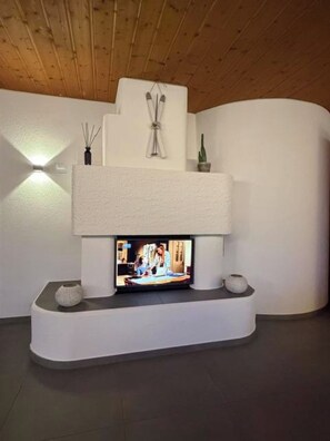 A modern fireplace with a flat-screen TV, white walls, and a wooden ceiling. - Alba Appartement/Fewo, Dusche und Bad, WC, 1 Schlafraum 2.5-Zimmerwohnung by Interhome (Frutigen)