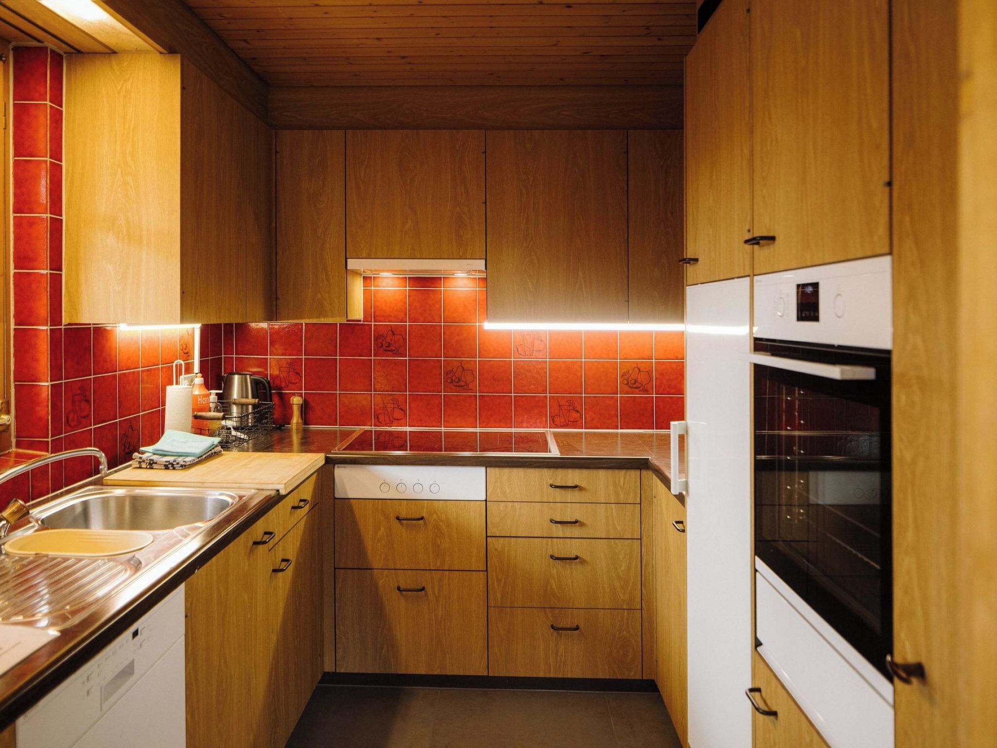 A compact kitchen with wooden cabinets, a built-in oven, and a dishwasher.