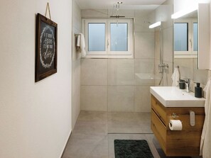 Ein modernes Badezimmer mit Dusche, Waschbecken und Spiegel.
