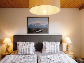 A bedroom with a bed, two bedside lamps, a framed picture on the wall, and a wooden ceiling. - Alba Appartement/Fewo, Dusche und Bad, WC, 1 Schlafraum 2.5-Zimmerwohnung by Interhome (Frutigen)