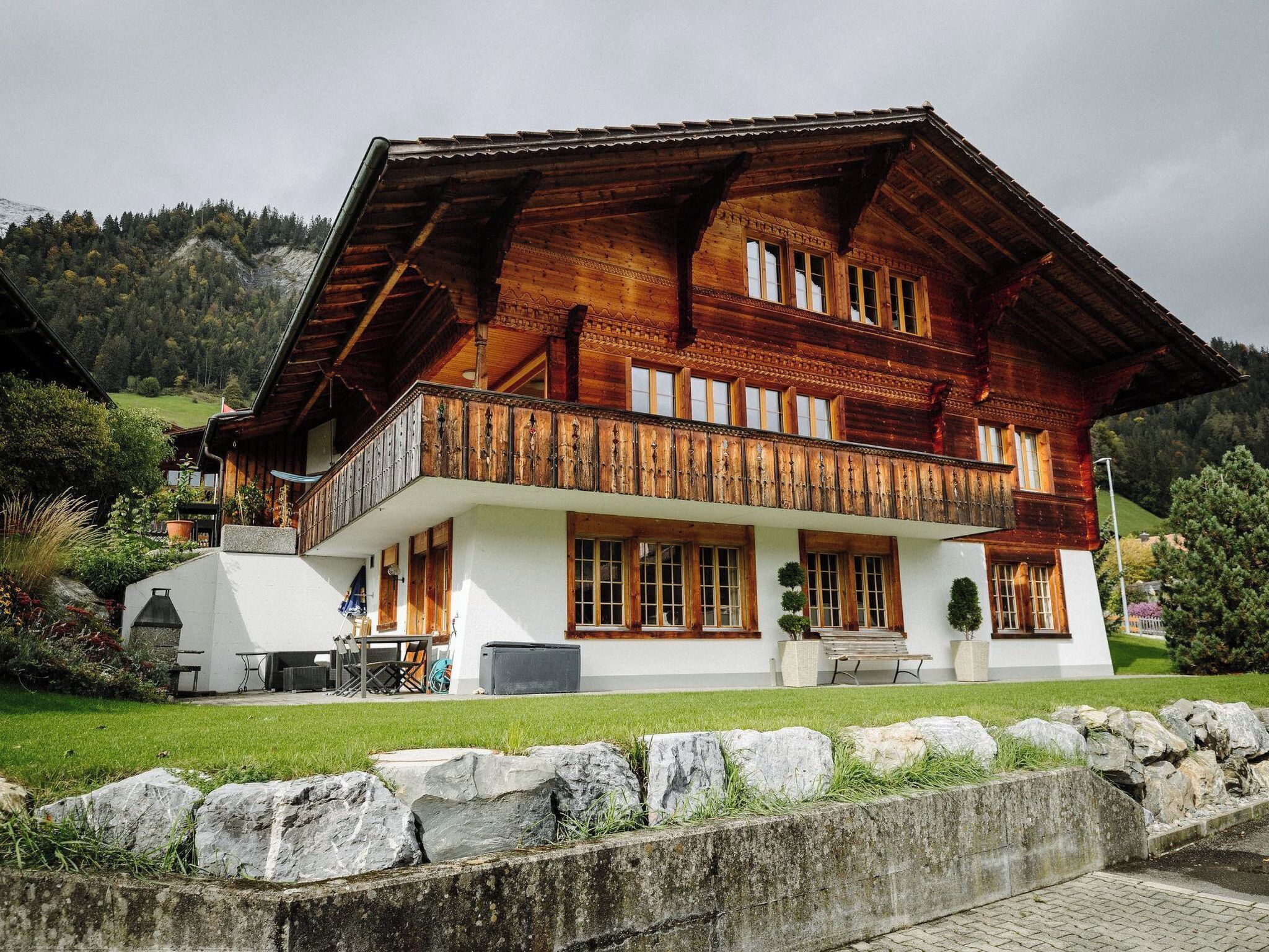 Un grand chalet en bois doté d’un balcon, de murs blancs et de fondations en pierre.