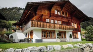 Een ruime houten chalet met balkon, witte muren en een stenen fundering.