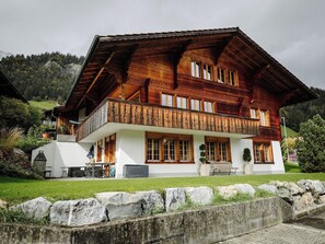 Eine große Holzhütte mit Balkon, weißen Wänden und einem Steinfundament.