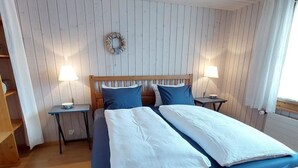 A double bed with a wooden frame, two bedside tables with lamps, and a wall-mounted decoration. - Chalet Edelweiss Appartement/Fewo, Dusche, WC, 2 Schlafräume 3-Zimmerwohnung by Interhome (Frutigen)