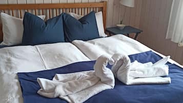 Un lit bien fait, avec une couvre-lit bleue et des oreillers blancs, une tête de lit en bois, une petite table de chevet avec une lampe et une couronne décorative accrochée au mur.