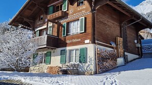 A wooden chalet with a balcony, a sign reading 'Da Liebe Gott macht schöne Dinge,' and a mountain backdrop. - Chalet Edelweiss Appartement/Fewo, Dusche, WC, 2 Schlafräume 3-Zimmerwohnung by Interhome (Frutigen)