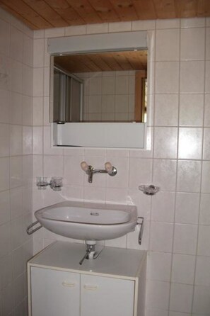 A bathroom with a white sink, a mirror above it, and a cabinet below. - Gehret Appartement/Fewo, Dusche, WC, 1 Schlafraum 2-Zimmerwohnung by Interhome (Adelboden)