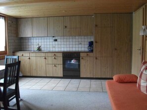 A compact kitchen with wooden cabinets, a tiled backsplash, and a built-in oven. - Gehret Appartement/Fewo, Dusche, WC, 1 Schlafraum 2-Zimmerwohnung by Interhome (Adelboden)