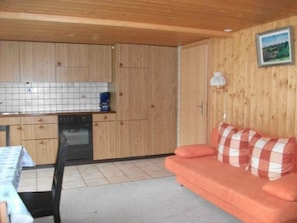 A compact kitchen with wooden cabinets, a dishwasher, and a tiled backsplash. - Gehret Appartement/Fewo, Dusche, WC, 1 Schlafraum 2-Zimmerwohnung by Interhome (Adelboden)